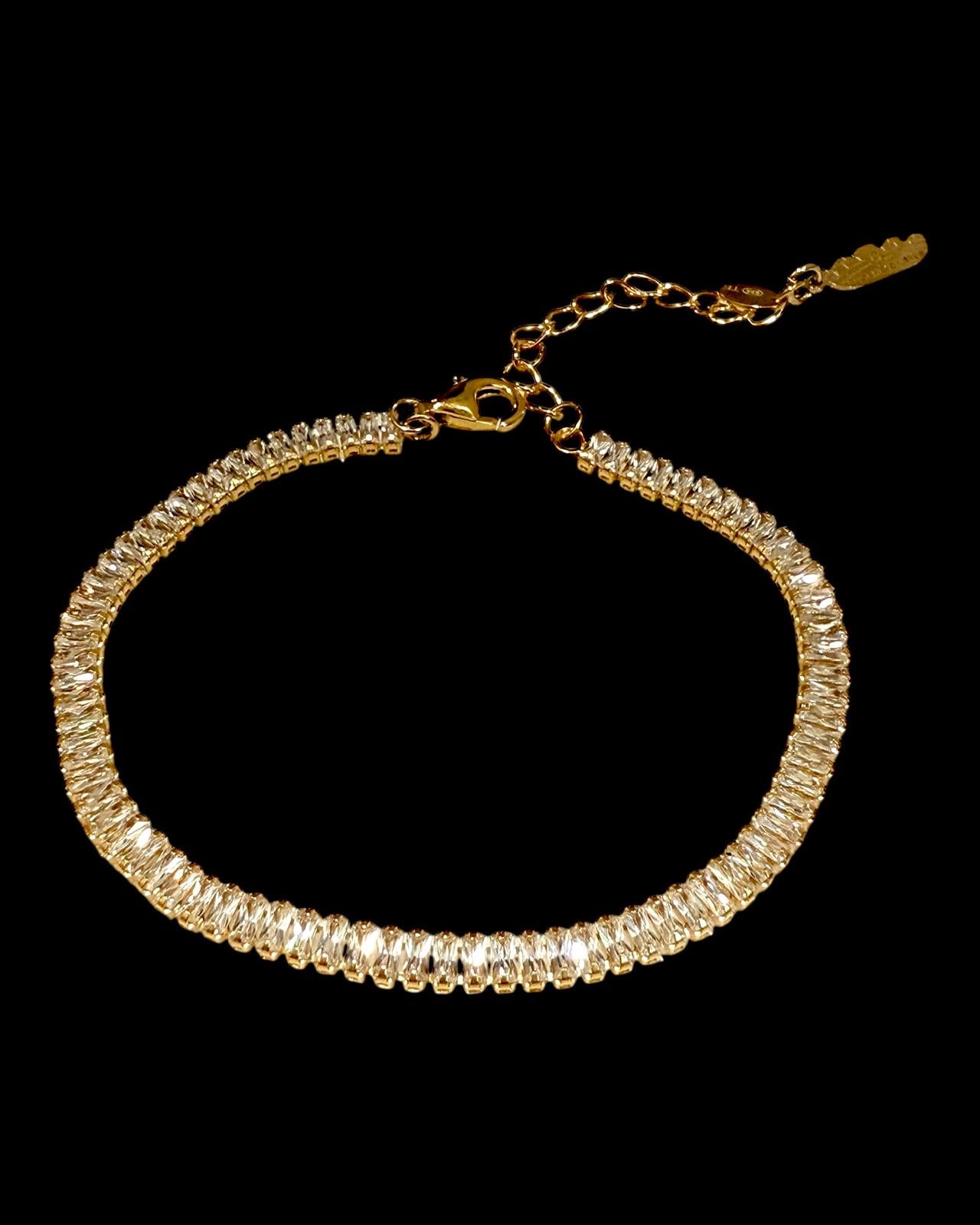 Pulseira dourada com brilhantes em corte baguete sobre fundo preto